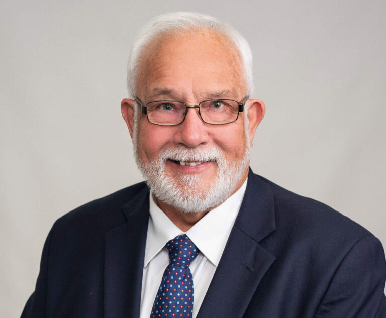 Senior man in professional attire smiling for the camera.