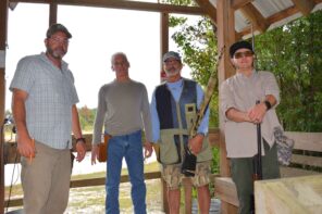 Group of men at the Day of Clays 2025 event, outdoors under a wooden shelter.