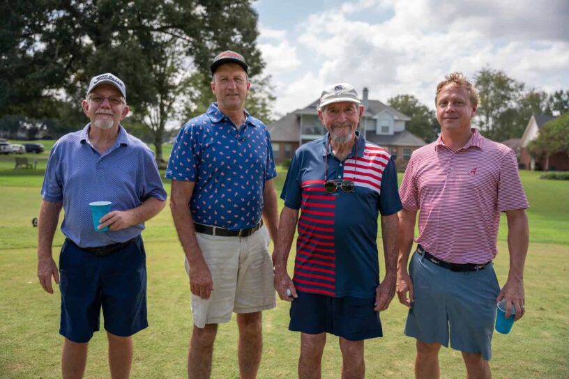 Joe Keezel, Steve Skipper, Tommy Lee, and Todd McArthur of Team AMA Lighting pose together on a golf course.