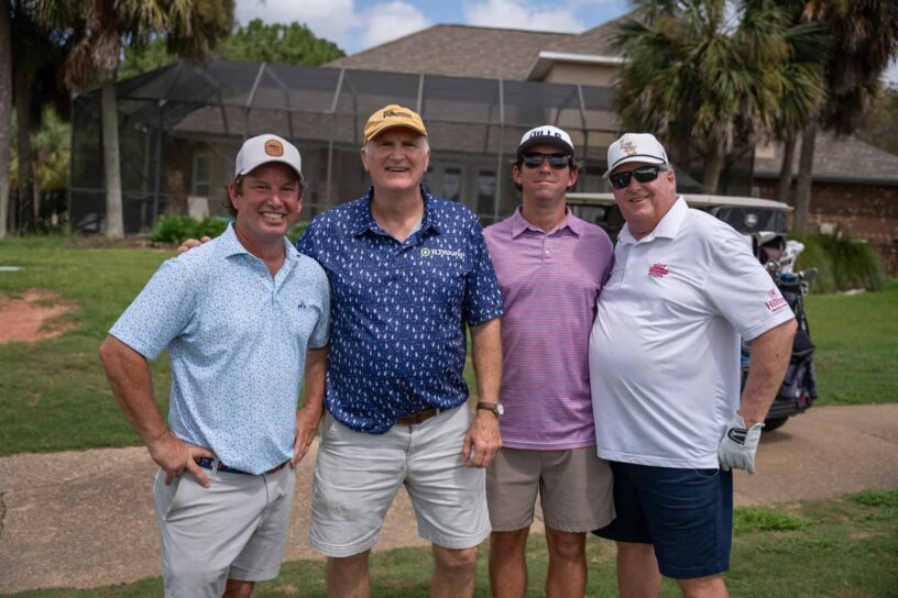 Randall Richardson, Charlie Sherrill Jr., Will Neuner, and Tony Neuner of Team Charlie Sherrill Jr. pose together on a golf course.
