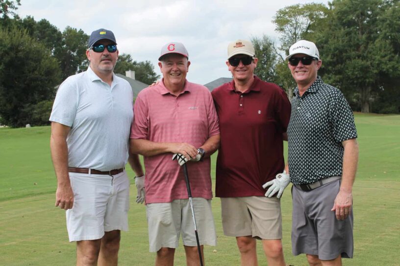 Kevin Sluder, Jeff Woodward, Chris Woodward, and Bobby Emmanuel of Team Gene's Floor Covering pose together on a golf course.