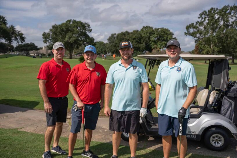 Leon Jernigan, Daniel Miller, Nathan Cobb, and Dennis Hurst of Team Police Benevolent Association pose together on a golf course.
