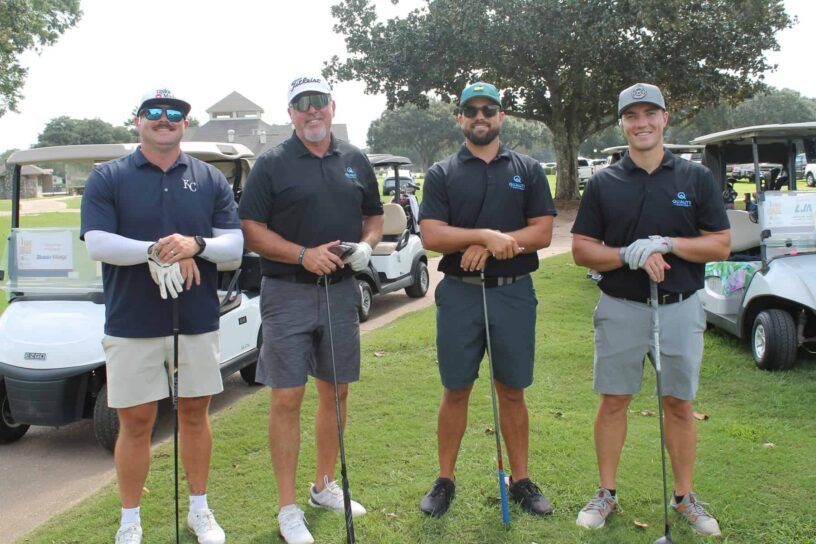 Nigel Ellis, Gregg Steed, Stephen Moore, and Jason Millar of Team Quality Roofing Solutions pose together on a golf course.
