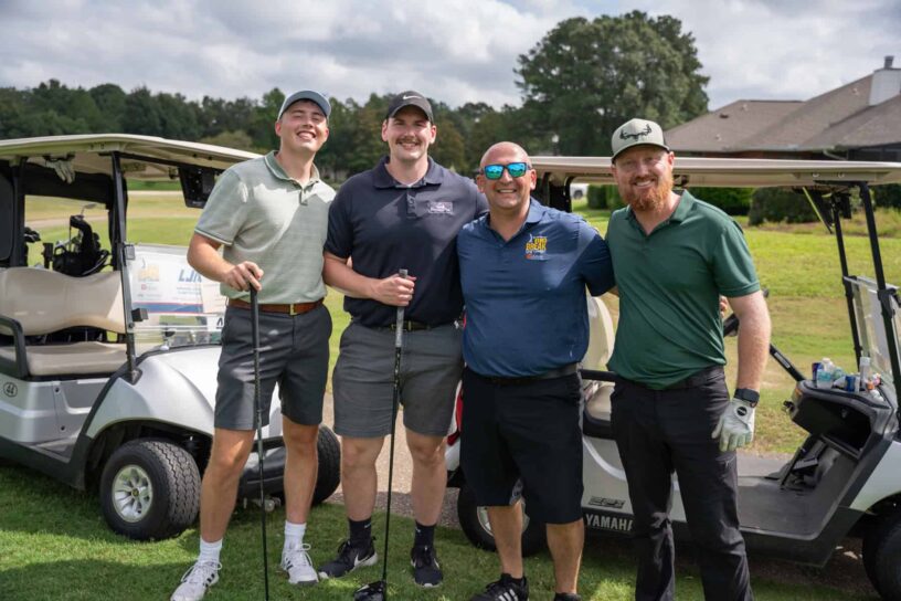Danny Penosky, Chase Steelman, Mark McMahon, and Jason Coster of Team SkyWarrior Flight Training pose together on a golf course.