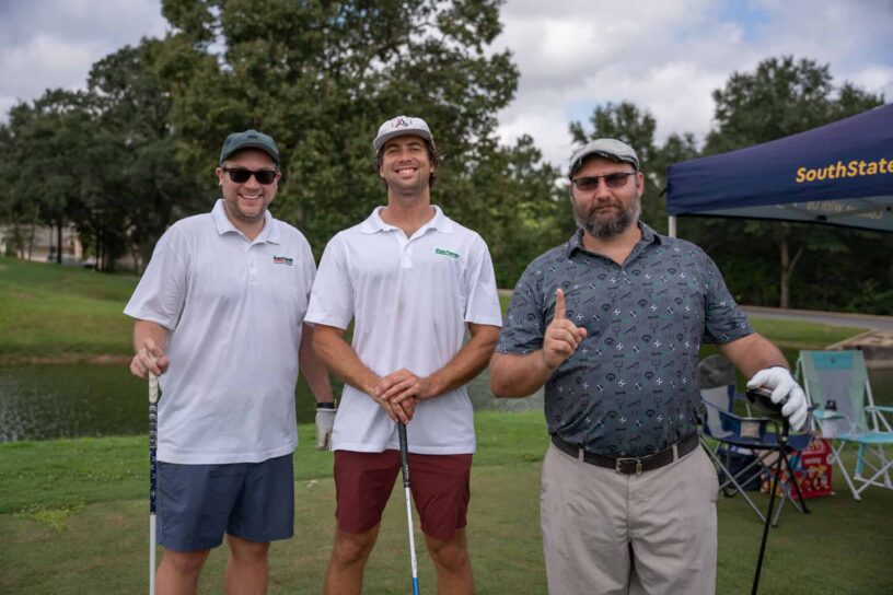 Nathan Kercher, Jake Meisenheimer, and Austin Tipton of Team Sunfarm and ForeverLawn pose together on a golf course.