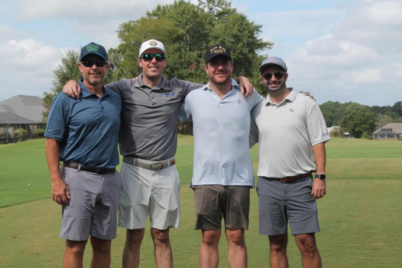 Jeff Crigler, Reid Torgersen, Mason Barnes, and Ashton Mitchell of Team Torgersen Consulting pose together on a golf course.