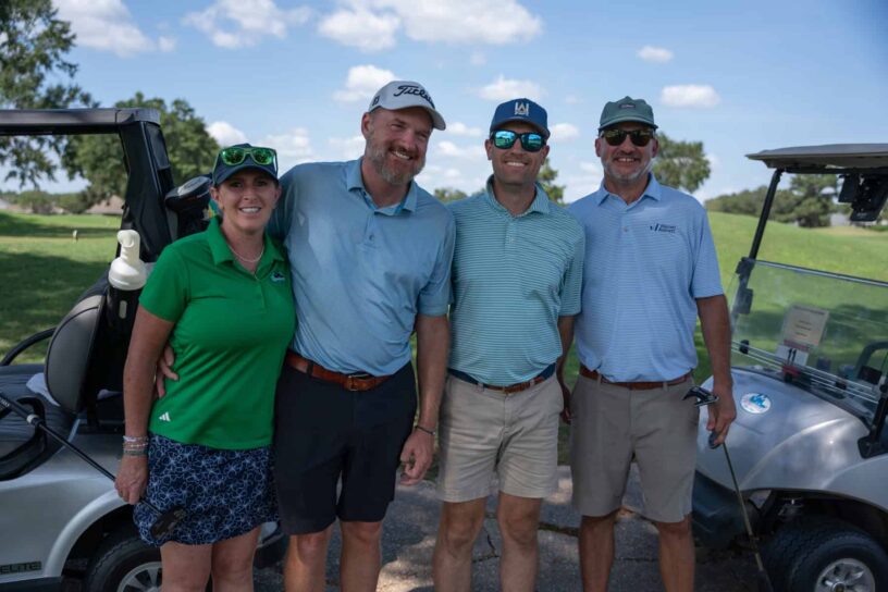 Robin Dezarn, Mike Dezarn, Alex Niedermayer, and Scott Warren of Team Underwood Anderson pose together on a golf course.