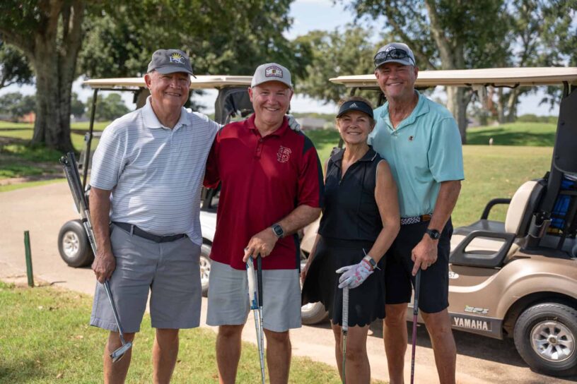 Denis McKinnon Sr., Denis McKinnon Jr., Lessa McKinnon, and Scott McKinnon of Team Veterans National Homecare #1 pose together on a golf course.