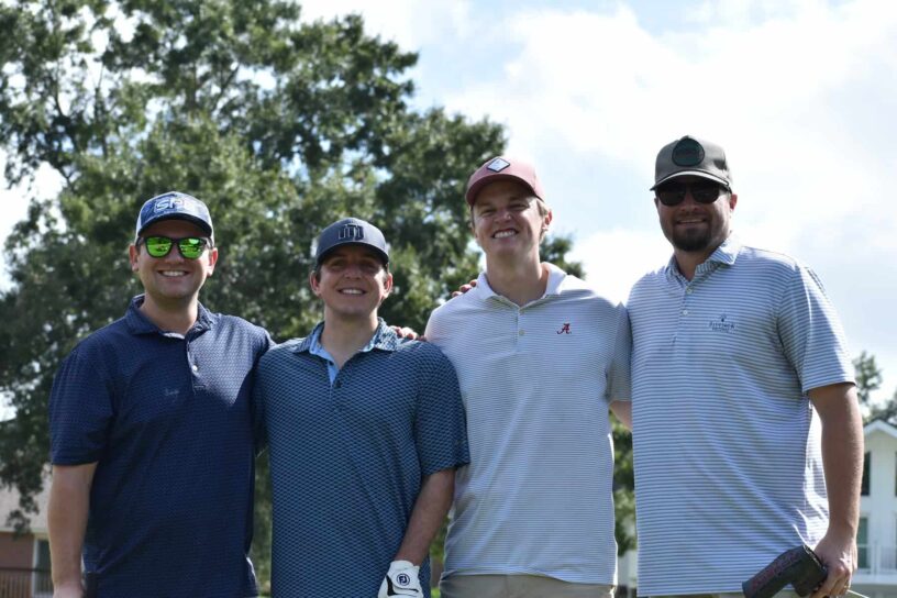 Denis McKinnon III, Cole Wilson, Zach Etheridge, and Joe Driver of Team Veterans National Homecare #2 pose together on a golf course.